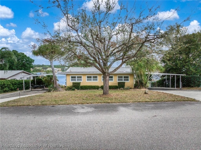 view of front of property featuring driveway, metal roof, and a front yard