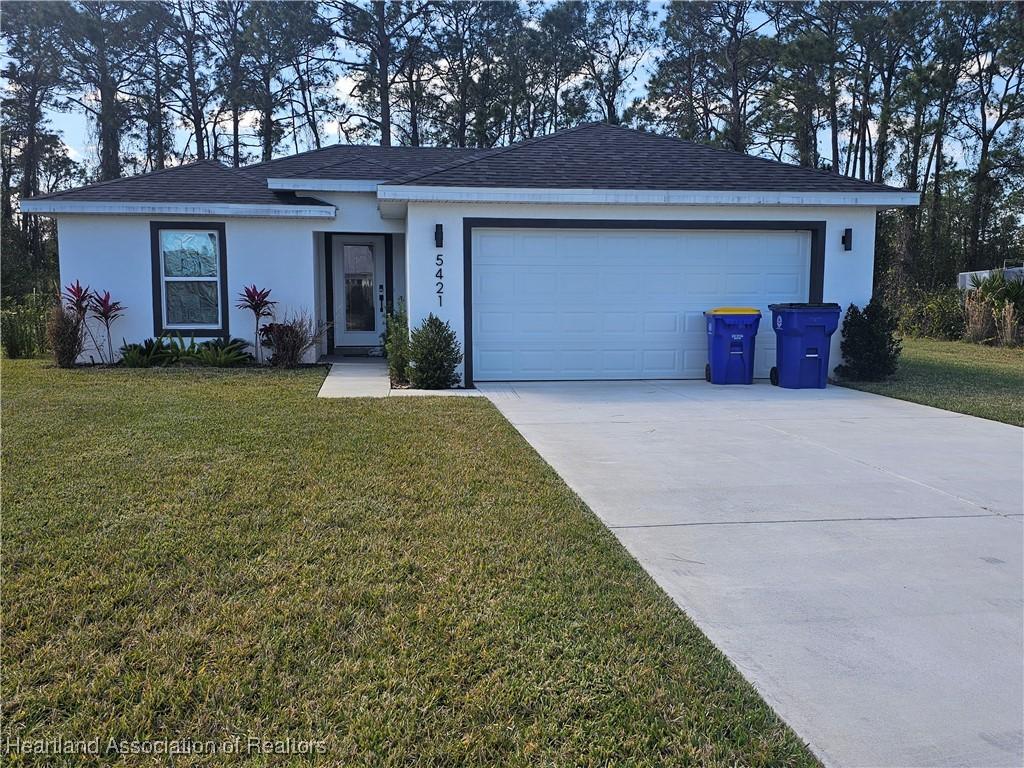 single story home featuring a garage and a front yard