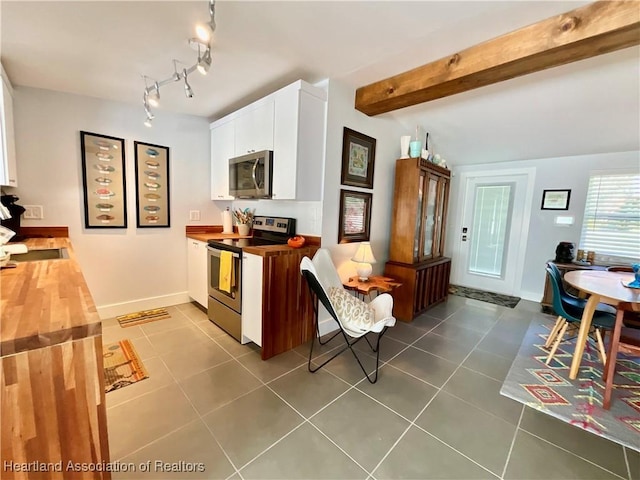 510 Lake June Rd, Lake Placid, FL 33852 - kitchen with beam ceiling, butcher block counters, stainless steel appliances, white cabinets, and dark tile patterned flooring