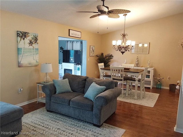 living room with baseboards, lofted ceiling, wood finished floors, and ceiling fan with notable chandelier