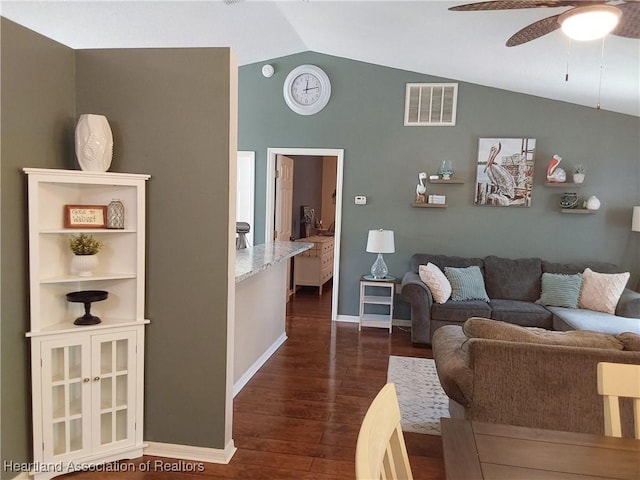 living area featuring dark wood-type flooring, visible vents, vaulted ceiling, and a ceiling fan
