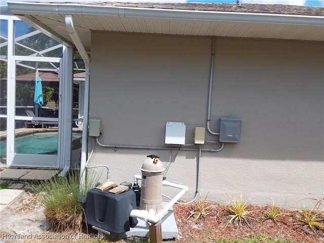 exterior details with stucco siding, a pool, and pump