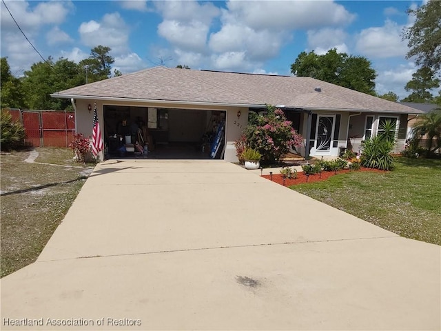 ranch-style house featuring driveway, fence, a garage, a front yard, and stucco siding