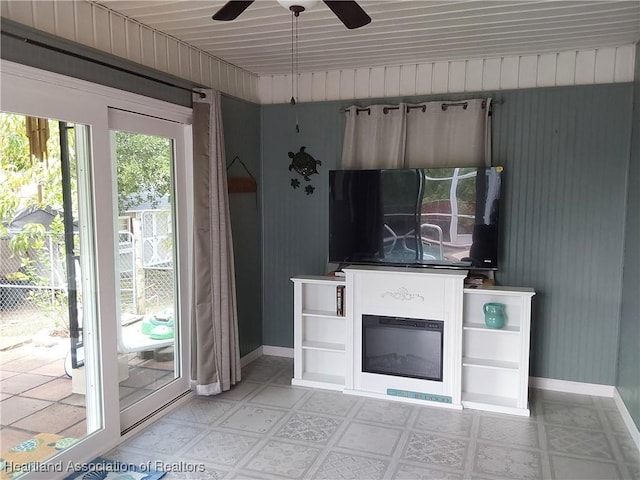 unfurnished living room with baseboards, light floors, and a ceiling fan