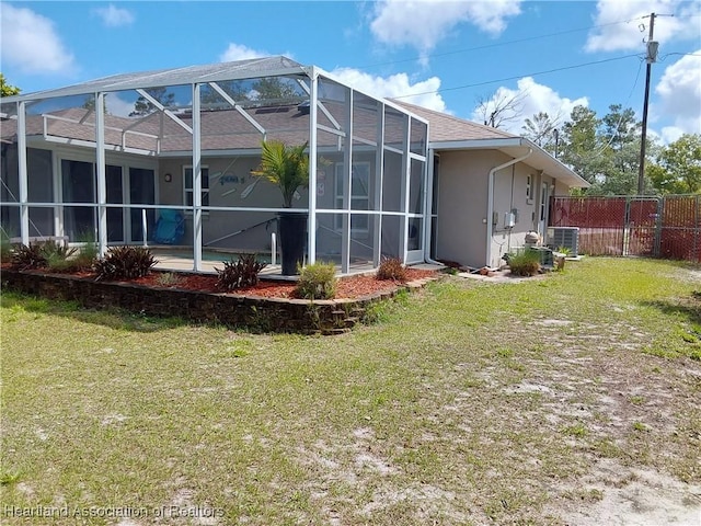 rear view of house featuring glass enclosure, cooling unit, stucco siding, fence, and a yard
