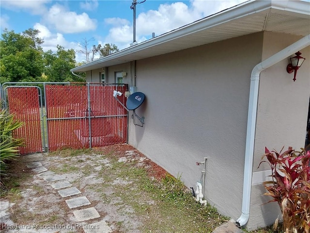 view of side of property featuring stucco siding and fence