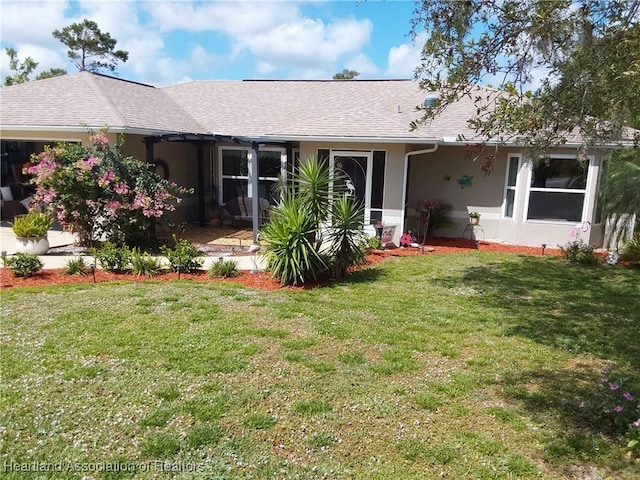 rear view of property with roof with shingles, stucco siding, and a yard