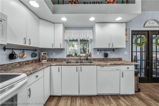 kitchen featuring sink, white appliances, light hardwood / wood-style flooring, white cabinetry, and french doors