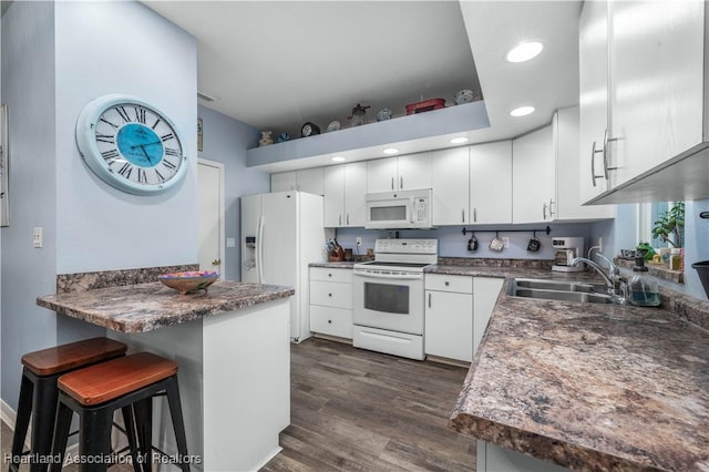 kitchen featuring a breakfast bar, sink, white cabinetry, kitchen peninsula, and white appliances