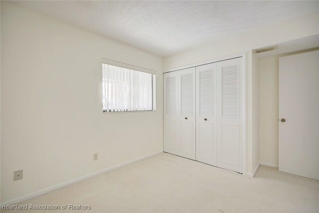 5544 Matanzas Dr, Sebring, FL 33872 - unfurnished bedroom with carpet flooring, a closet, a textured ceiling, and baseboards
