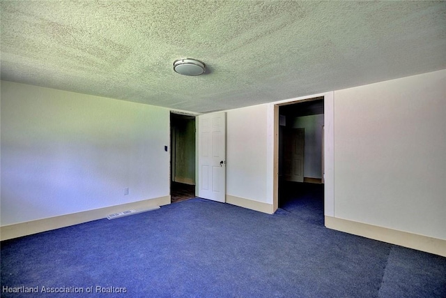 unfurnished room with dark carpet and a textured ceiling