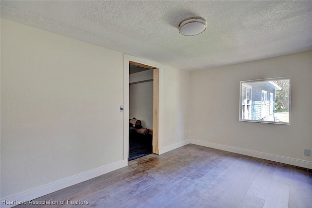 unfurnished bedroom featuring hardwood / wood-style floors, a textured ceiling, and a closet