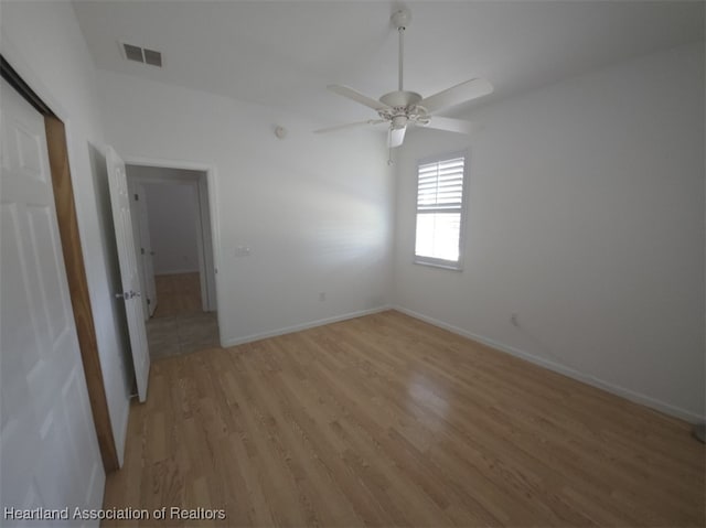 empty room featuring baseboards, a ceiling fan, visible vents, and light wood-style floors