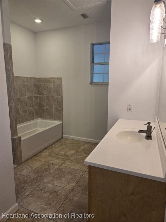 bathroom with a garden tub, baseboards, visible vents, and vanity