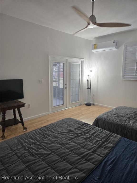 bedroom featuring a ceiling fan, baseboards, wood finished floors, and a wall mounted AC