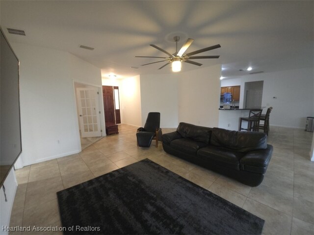 living room featuring light tile patterned floors, baseboards, visible vents, and a ceiling fan