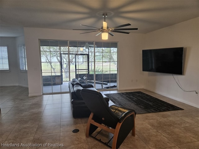 living area featuring tile patterned flooring, baseboards, and ceiling fan