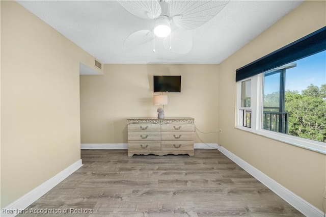 unfurnished room with ceiling fan, light hardwood / wood-style flooring, and a textured ceiling