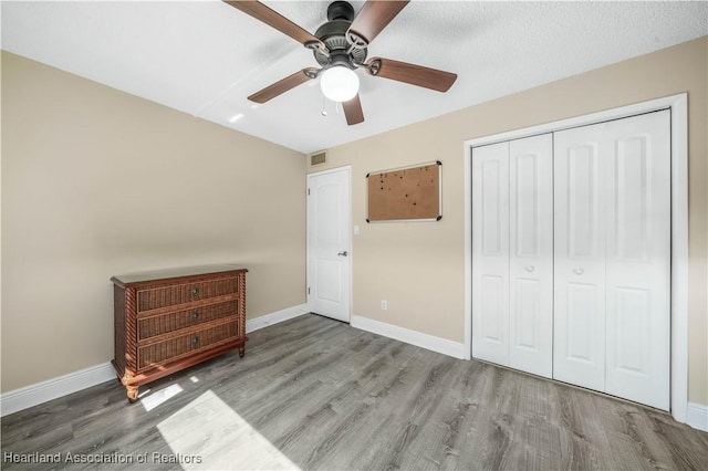 unfurnished bedroom featuring ceiling fan, a closet, hardwood / wood-style floors, and a textured ceiling