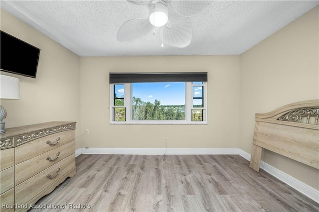 bedroom with a textured ceiling, light hardwood / wood-style floors, and ceiling fan