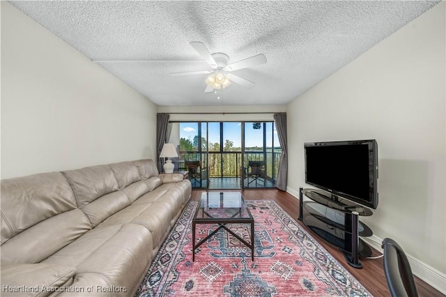 living room featuring wood-type flooring, a textured ceiling, and ceiling fan