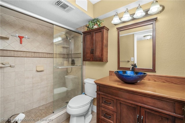 bathroom with a shower with door, vanity, and toilet