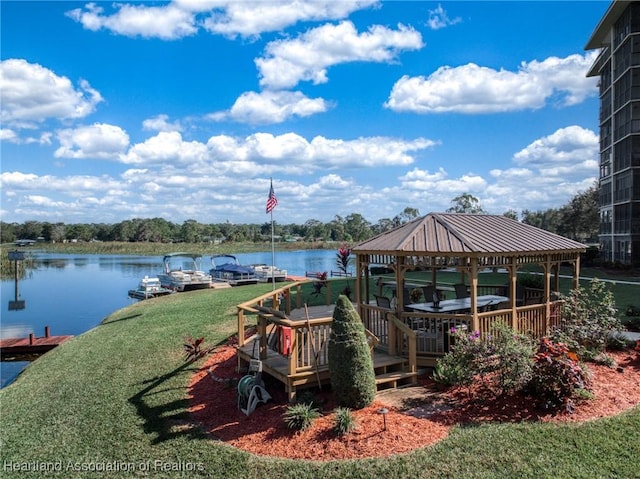 dock area with a gazebo, a water view, and a lawn