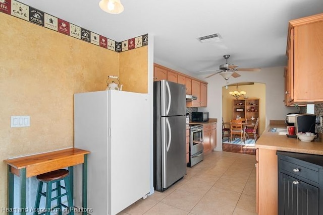 kitchen with appliances with stainless steel finishes, ceiling fan with notable chandelier, and light tile patterned floors