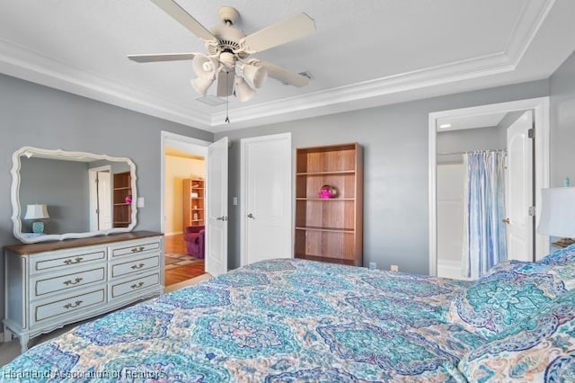 bedroom with a tray ceiling, crown molding, and ceiling fan