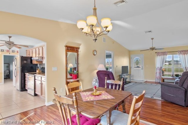 dining area with lofted ceiling, ceiling fan with notable chandelier, and light hardwood / wood-style flooring