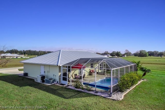 rear view of house with central air condition unit, glass enclosure, and a lawn