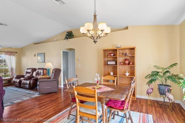 dining area featuring an inviting chandelier, wood-type flooring, and vaulted ceiling