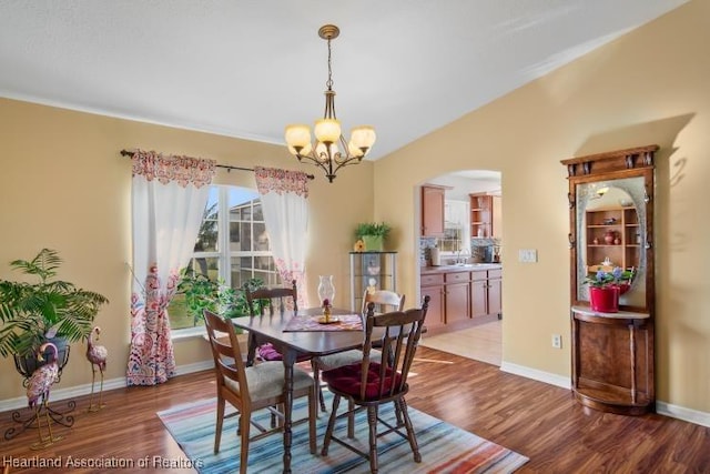 dining space featuring lofted ceiling, hardwood / wood-style floors, and an inviting chandelier