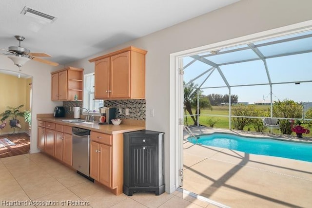 kitchen featuring sink, light tile patterned floors, dishwasher, ceiling fan, and backsplash