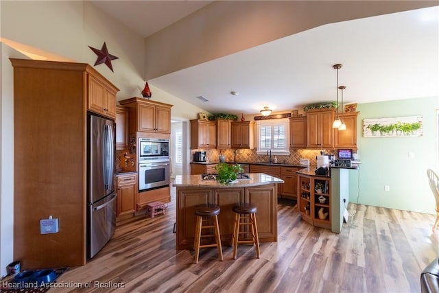 112 Wild Duck Pt, Lorida, FL 33857 - kitchen featuring appliances with stainless steel finishes, a kitchen island, brown cabinets, light wood-style flooring, and lofted ceiling