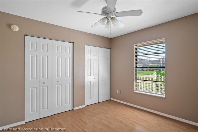 unfurnished bedroom with two closets, ceiling fan, and light hardwood / wood-style floors