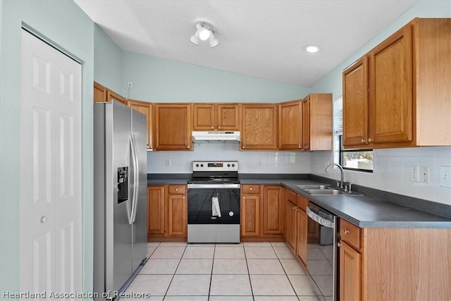 kitchen featuring sink, stainless steel appliances, lofted ceiling, decorative backsplash, and light tile patterned floors