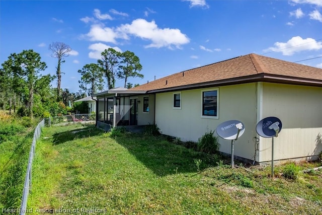 rear view of house with a sunroom and a yard