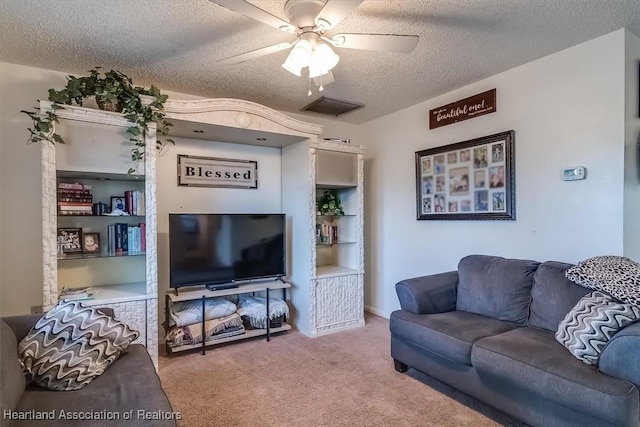 carpeted living room featuring ceiling fan and a textured ceiling