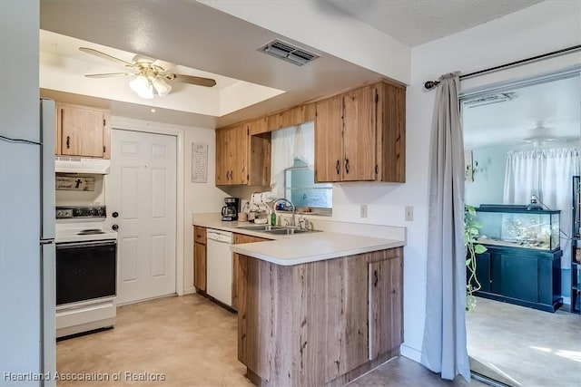 kitchen with sink, white appliances, ceiling fan, a raised ceiling, and kitchen peninsula