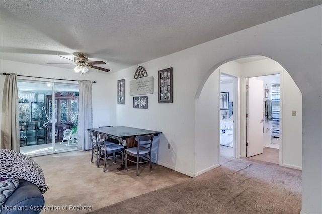 dining space with ceiling fan, carpet floors, and a textured ceiling