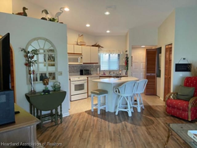 kitchen featuring range, tasteful backsplash, a breakfast bar area, a kitchen island, and hardwood / wood-style flooring