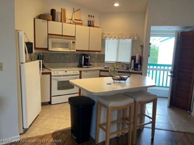 kitchen with white appliances, backsplash, and light tile patterned floors