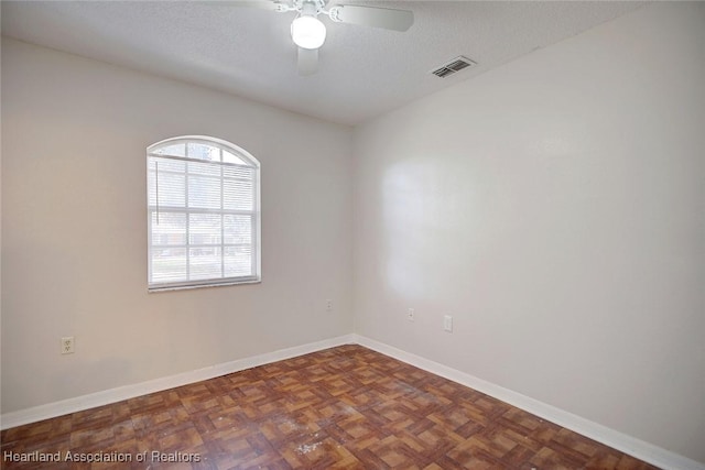 spare room with ceiling fan, dark parquet floors, and a textured ceiling