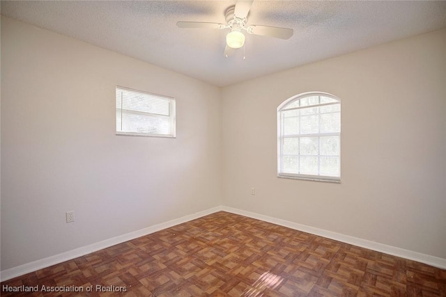 spare room with ceiling fan, dark parquet floors, and a textured ceiling