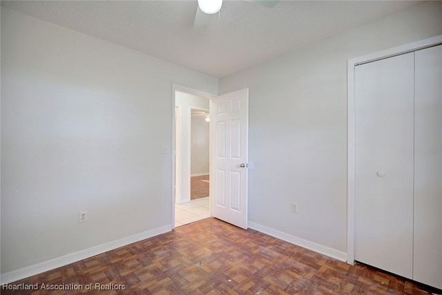 unfurnished bedroom featuring light parquet flooring, a closet, and ceiling fan