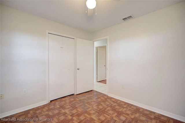 unfurnished bedroom featuring a textured ceiling, a closet, light parquet floors, and ceiling fan