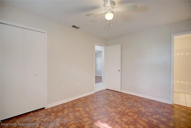 unfurnished bedroom featuring ceiling fan, a closet, a textured ceiling, and parquet flooring