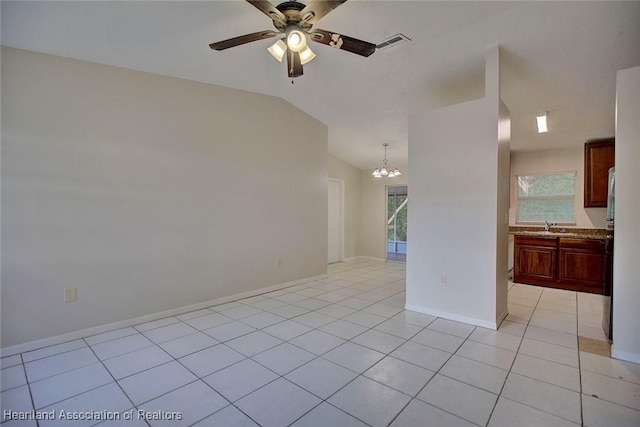 empty room with light tile patterned floors, ceiling fan with notable chandelier, vaulted ceiling, and sink