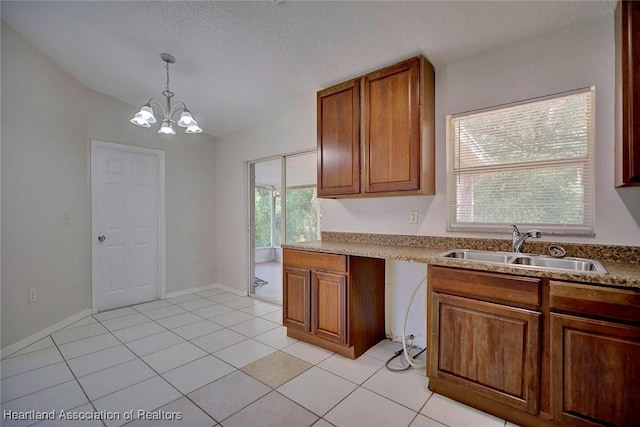 kitchen with sink, a notable chandelier, a textured ceiling, decorative light fixtures, and light tile patterned floors